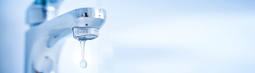 Nahaufnahme eines Wasserhahns mit einer einzelnen Wassertropfenformation.